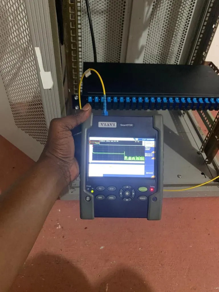 Engineer taking a reading on a handheld OTDR at a fibre cabinet